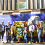 The Brixton House staff team stand in front of the building hoardings