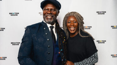 New Chair Designate Levi Roots, smiling with Delia Barker at Brixton House in front of a Brixton House step and repeat banner